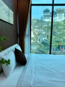 a bedroom with a white bed with a large window at Lightning Riverside in Hanoi