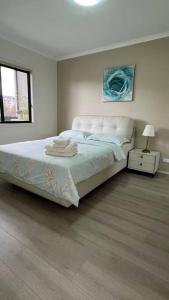 a white bedroom with a bed and a lamp at Centro Gungahlin in Harrison