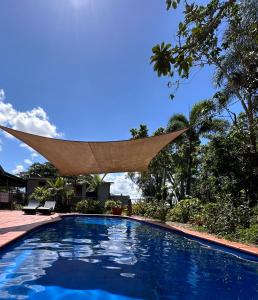 a swimming pool with a triangular shade over it at Feng Shui Sugarcane Cabin in Proserpine