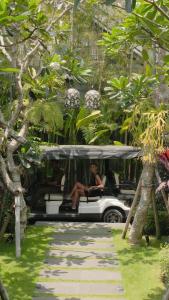 uma mulher sentada na parte de trás de um carrinho de golfe em La Reserve 1785 Canggu Beach em Canggu