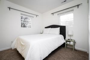 a white bedroom with a bed and two windows at Centrally Located 3BD Urban Oasis in Indianapolis