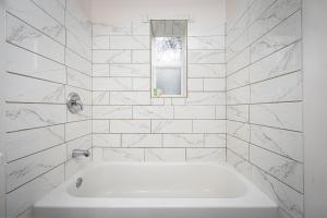 a white bathroom with a tub and a window at Centrally Located 3BD Urban Oasis in Indianapolis +16 photos
