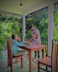 un homme et une femme assis à une table en bois dans l'établissement Nature Green Hotels On Rock Home Ella, à Ella