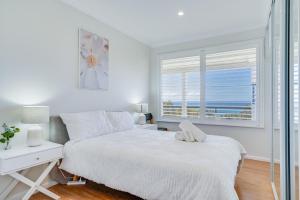 a white bedroom with a bed and a window at Becker Bliss - Ocean views, 5 bedrooms, sleeps 12 in Forster