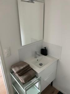 een witte badkamer met een wastafel en een spiegel bij Studio 304 - Hyper Centre - Intégralement rénové - Toutes commodités à pied in Saint-Nazaire