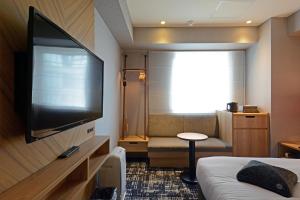 a hotel room with a flat screen tv and a bed at Hotel Forza Osaka Kitahama in Osaka