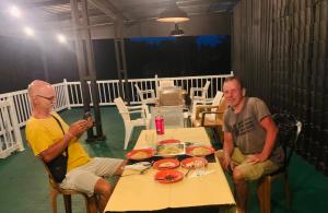 deux hommes assis à une table sur un patio dans l'établissement Hotel Change Badulla, à Badulla
