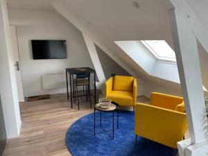 uma sala de estar com cadeiras amarelas e uma televisão em Studio 303 - Hyper Centre - Intégralement rénové - Toutes commodités à pied em Saint-Nazaire