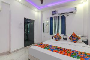 een slaapkamer met twee bedden met kleurrijke kussens erop bij FabExpress Hanuman Ji in Ayodhya