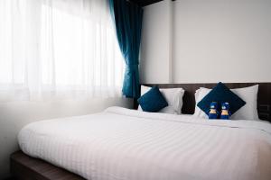 1 dormitorio con 1 cama blanca grande con almohadas azules en BearPacker Patong Hostel en Patong