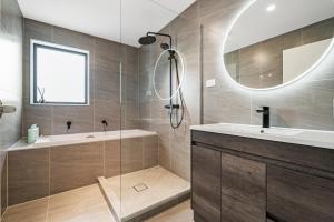 uma casa de banho com uma banheira, um lavatório e um espelho. em Charming Urban Townhouse Getaway em Auckland
