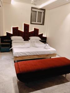 チェンナイにあるHotel AK International - Chennaiのベッドルーム(大型ベッド1台、赤いオットマン付)