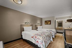 a hotel room with two beds and a desk at Red Roof Inn Detroit - Royal Oak/Madison Heights in Madison Heights