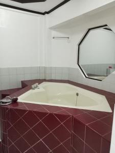 a bathroom with a tub and a mirror at Larot's Vacation House - Rooms Only in Siquijor