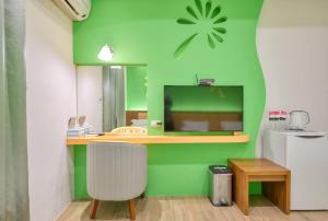 una habitación con una pared verde y una silla blanca en Easy Stay B&B, en Magong