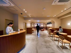 a man and a woman standing at a counter in a restaurant at Hotel Plus Hostel TOKYO ASAKUSA 2 in Tokyo