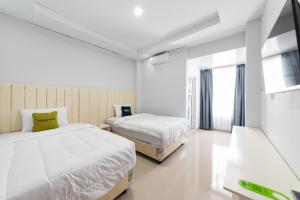 a bedroom with two beds and a window at Urbanview Hotel Ranls Dream Banda Aceh by RedDoorz in Banda Aceh