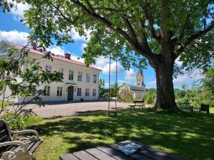 einen Park mit einem Baum und einer Bank und einem Gebäude in der Unterkunft Hoby Gård B&B in Bräkne-Hoby