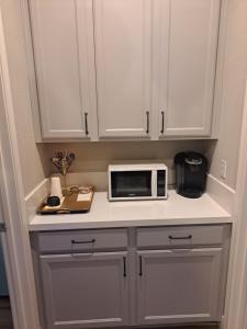 una cocina con armarios blancos y microondas en una encimera en In Law Unit, 2 bedroom Suite, en Roseville