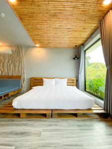 a bedroom with a large bed with a large window at Babylon Mini Resort in Vung Tau