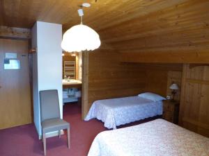 1 dormitorio con 2 camas, silla y lámpara en Hotel Floralp, en La Clusaz