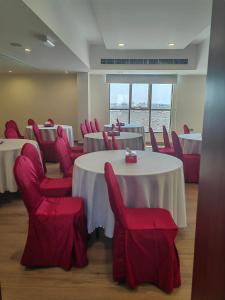 a conference room with tables and red chairs at ALYA Hotel in Barka