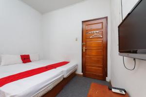a bedroom with a bed and a flat screen tv at RedDoorz Syariah @ Panglima Nyak Makam Aceh 2 in Banda Aceh