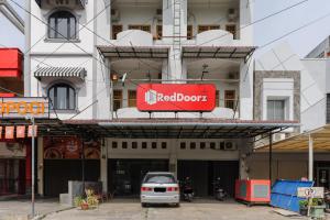 un edificio con un letrero de puerta roja en él en RedDoorz Syariah @ Panglima Nyak Makam Aceh 2, en Banda Aceh