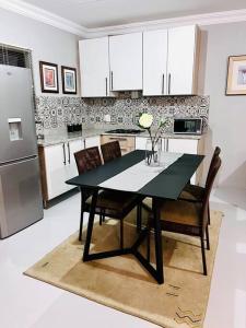 uma cozinha com uma mesa preta com cadeiras e um frigorífico em The Comfy Corner @ Skyfall Country Estate em Polokwane