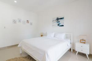 um quarto branco com uma cama branca e uma fotografia na parede em Villa Arya - Canggu em Canggu