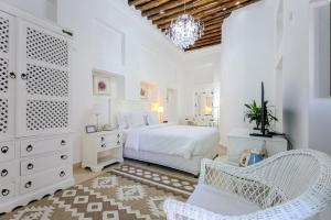 ein weißes Schlafzimmer mit einem Bett und einem Stuhl in der Unterkunft Arabian Boutique Hotel in Dubai