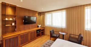 uma sala de estar com uma televisão e uma mesa e cadeiras em Hotel Uri& em Seul