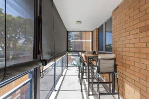 uma varanda com uma mesa e cadeiras e uma parede de tijolos em East Fremantle Escape em Fremantle