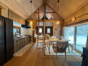 eine Küche und ein Esszimmer mit einem Tisch in einem Haus in der Unterkunft 美瑛森林木屋 - 小紅帽 in Biei
