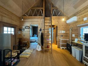 ein Zimmer mit Holzwänden und ein Schlafzimmer mit einem Bett in der Unterkunft 美瑛森林木屋 - 小紅帽 in Biei