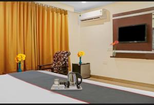 Zimmer mit einem Tisch, einem TV und einem Stuhl in der Unterkunft Hotel Raj vihar residency in Vijayawāda