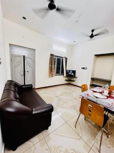 a living room with a leather couch and a table at Lumina Home Stay in Puducherry