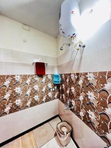a bathroom with a toilet and a flower patterned wall at Lumina Home Stay in Puducherry