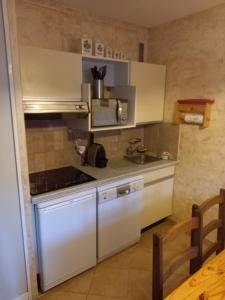 a kitchen with white cabinets and a sink at Residence "l'adret " l'alpe d'auron in Auron