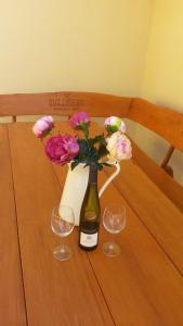 eine Flasche Wein mit Blumen und zwei Gläsern auf dem Tisch in der Unterkunft Siglisberg in Banská Štiavnica