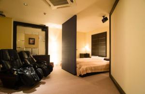 a bedroom with a bed and two black chairs at アルカディア in Maizuru