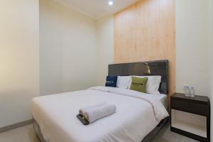 a bedroom with a white bed with a roll on it at Urbanview Hotel Mamifokobo Puncak in Sindanglaya