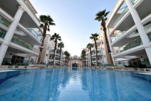ein großer Swimmingpool in einem großen Gebäude mit Palmen in der Unterkunft דירת גן על שפת הבריכה in Eilat