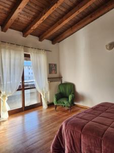 um quarto com uma cadeira verde e uma janela em Margiolà em Calalzo