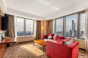 a living room with a red couch and large windows at Novotel Atlantis Shanghai in Shanghai