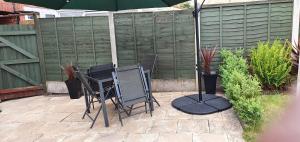 - 2 chaises et un parasol sur la terrasse dans l'établissement B43 Cosy Home - Contractor-Family Stays Near Bhm City-Off Road Parking Free Wi-fi, à Holly Lane