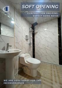 a bathroom with a white toilet and a sink at Maine City Residences Tramo in Manila