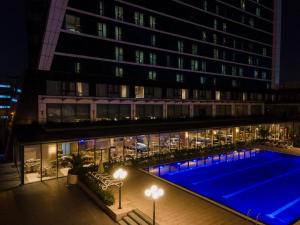 Windsor Hotel & Convention Center Istanbul في إسطنبول: مسبح امام مبنى في الليل