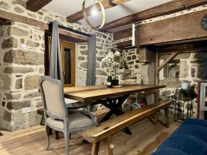 a dining room with a wooden table and a stone wall at Le Quatorze 