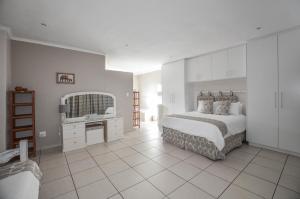 a white bedroom with a bed and a mirror at 9 on Dolfyn in Yzerfontein